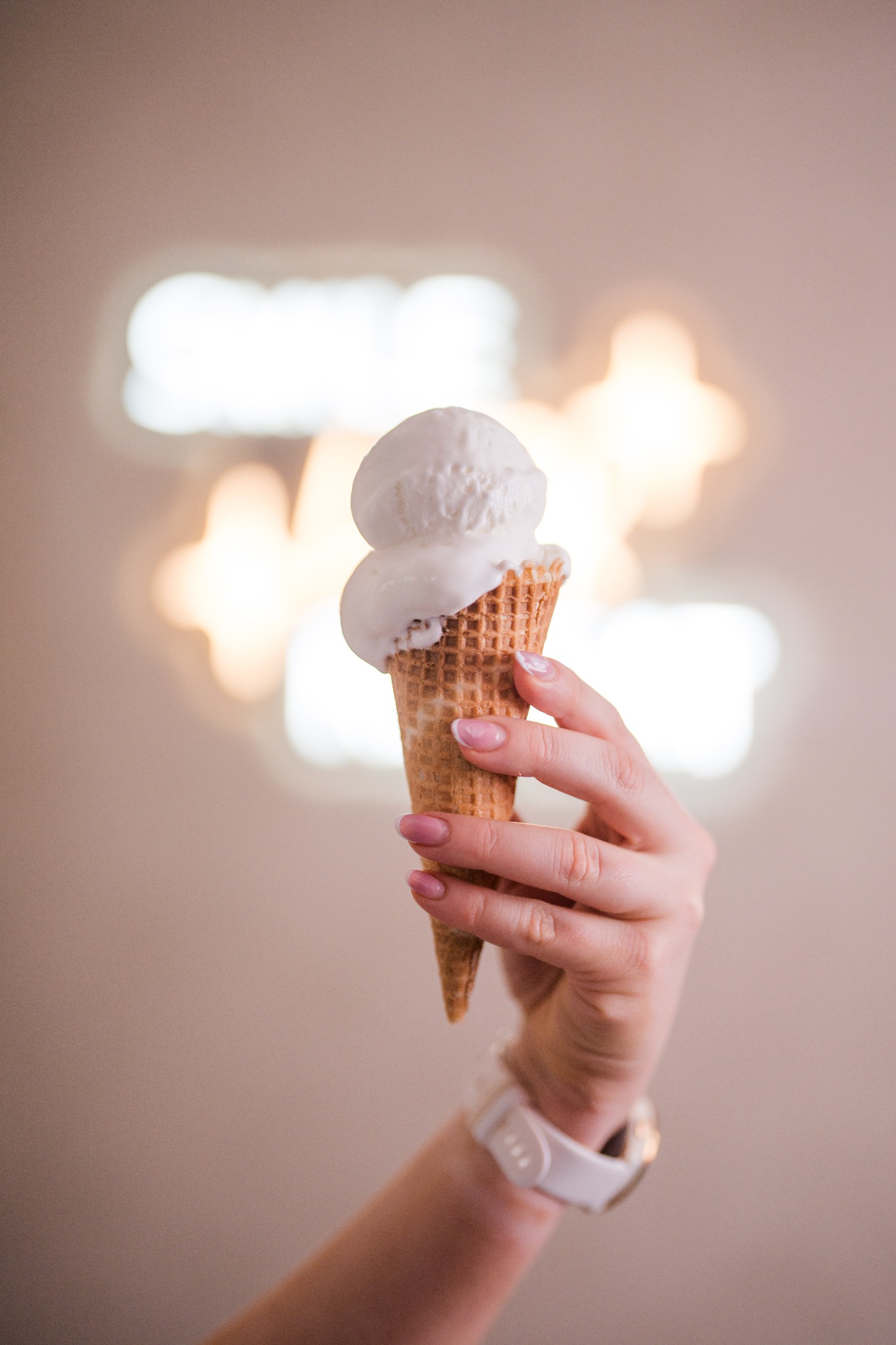 A vanilla ice cream cone held up against a softly lit background