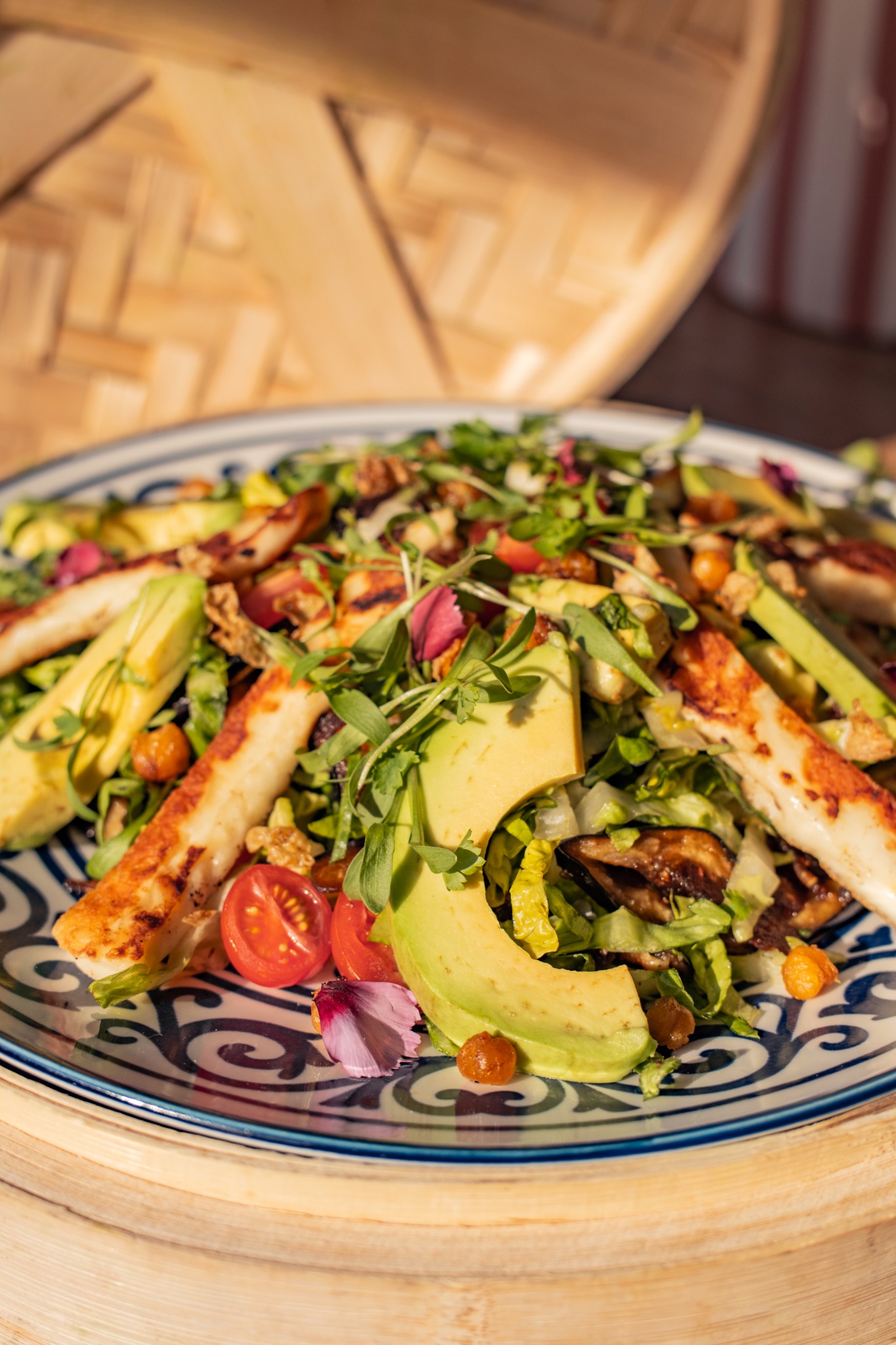 A fresh salad dish with avocado and grilled halloumi